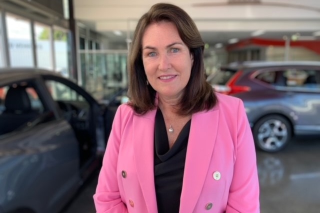 A smiling woman at a car dealership